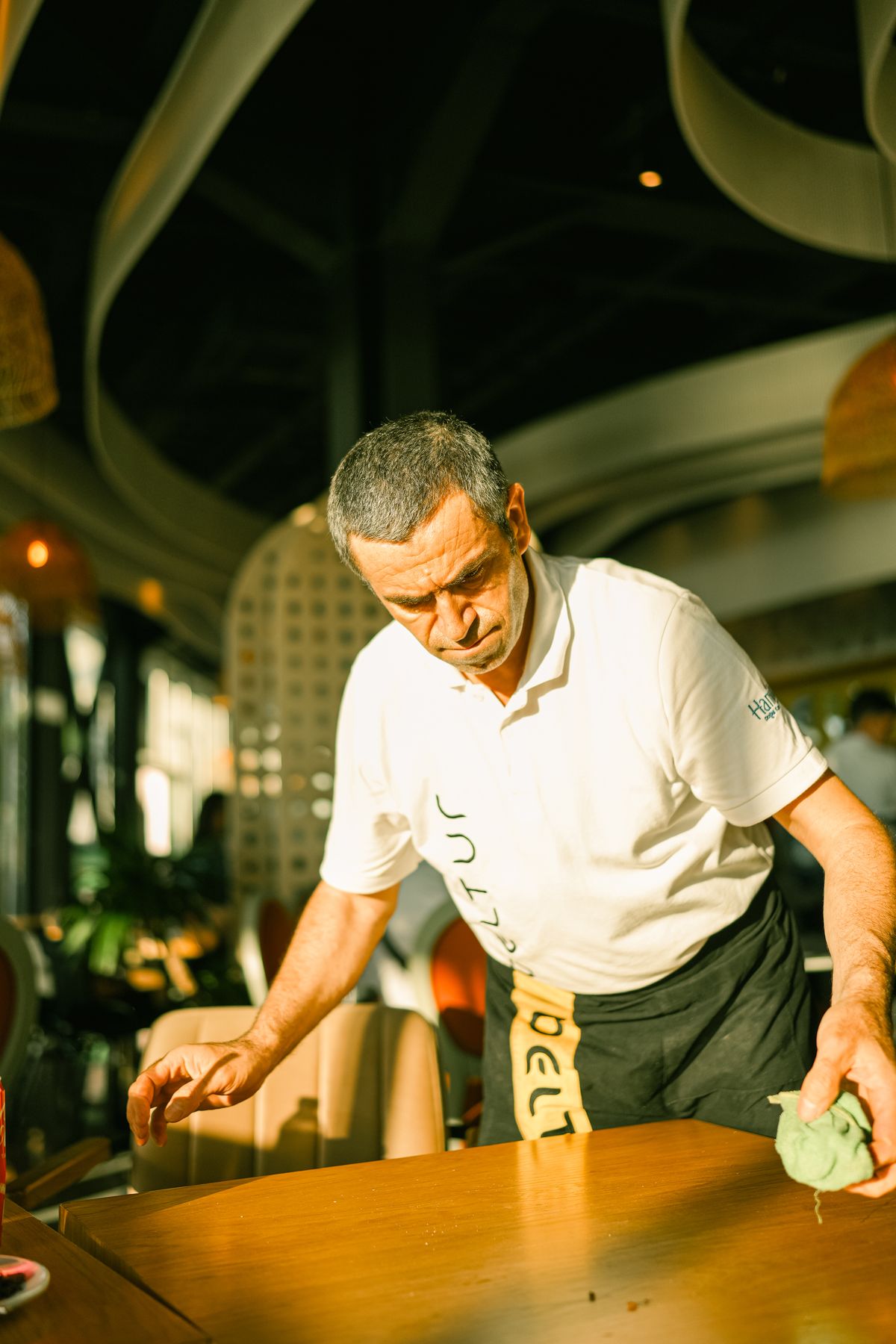 Hospitality staff member clearing and cleaning a table after service