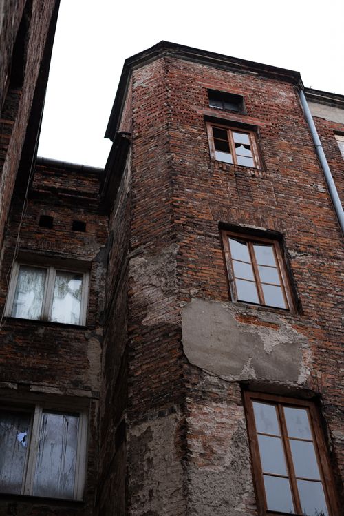 Free Low angle view of an old brick building with damaged facade and wooden framed windows. Stock Photo