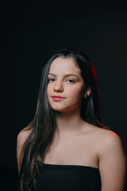 Free A striking portrait of a woman with long black hair, captured against a dark backdrop. Stock Photo