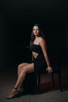 Stylish woman in black dress posing elegantly in a studio environment.