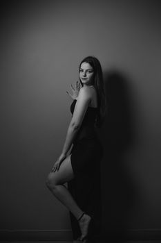 Sophisticated black dress fashion portrait of a young woman posing in a studio.