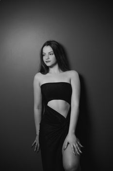 Black and white portrait of a young woman in elegant fashion posing in a studio setting.