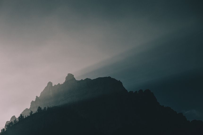 Silhouetted mountain ridge with light breaking through fog — eberhard grossgasteiger on Pexels