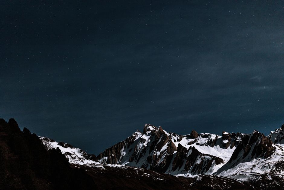 A breathtaking nighttime landscape of snow-covered mountains beneath a starry sky.