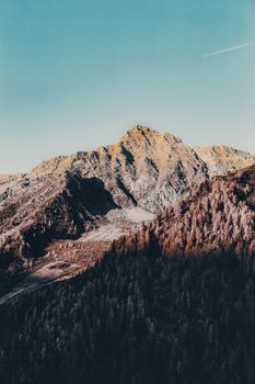 Breathtaking view of a rocky mountain with forested slopes under a clear blue sky.