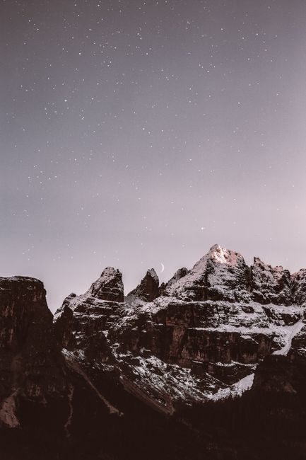 Majestic snow-covered mountain peaks illuminated under a starry night sky, creating a serene and breathtaking landscape.
