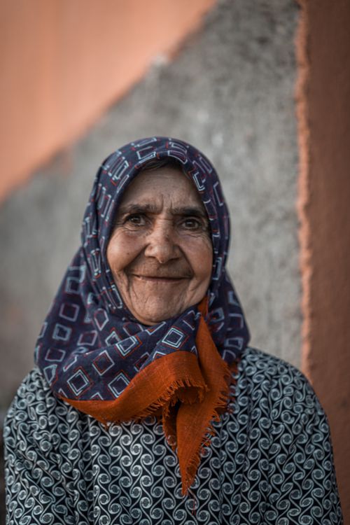Free Portrait of a senior woman with a joyful smile wearing a patterned headscarf. Stock Photo