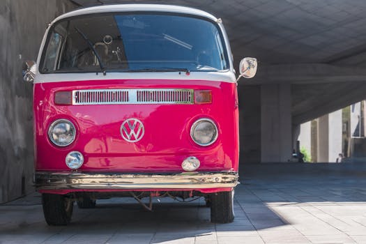 A classic red Volkswagen bus parked in a modern urban environment.
