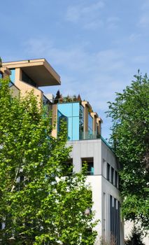 A contemporary building featuring a roof terrace surrounded by lush greenery.