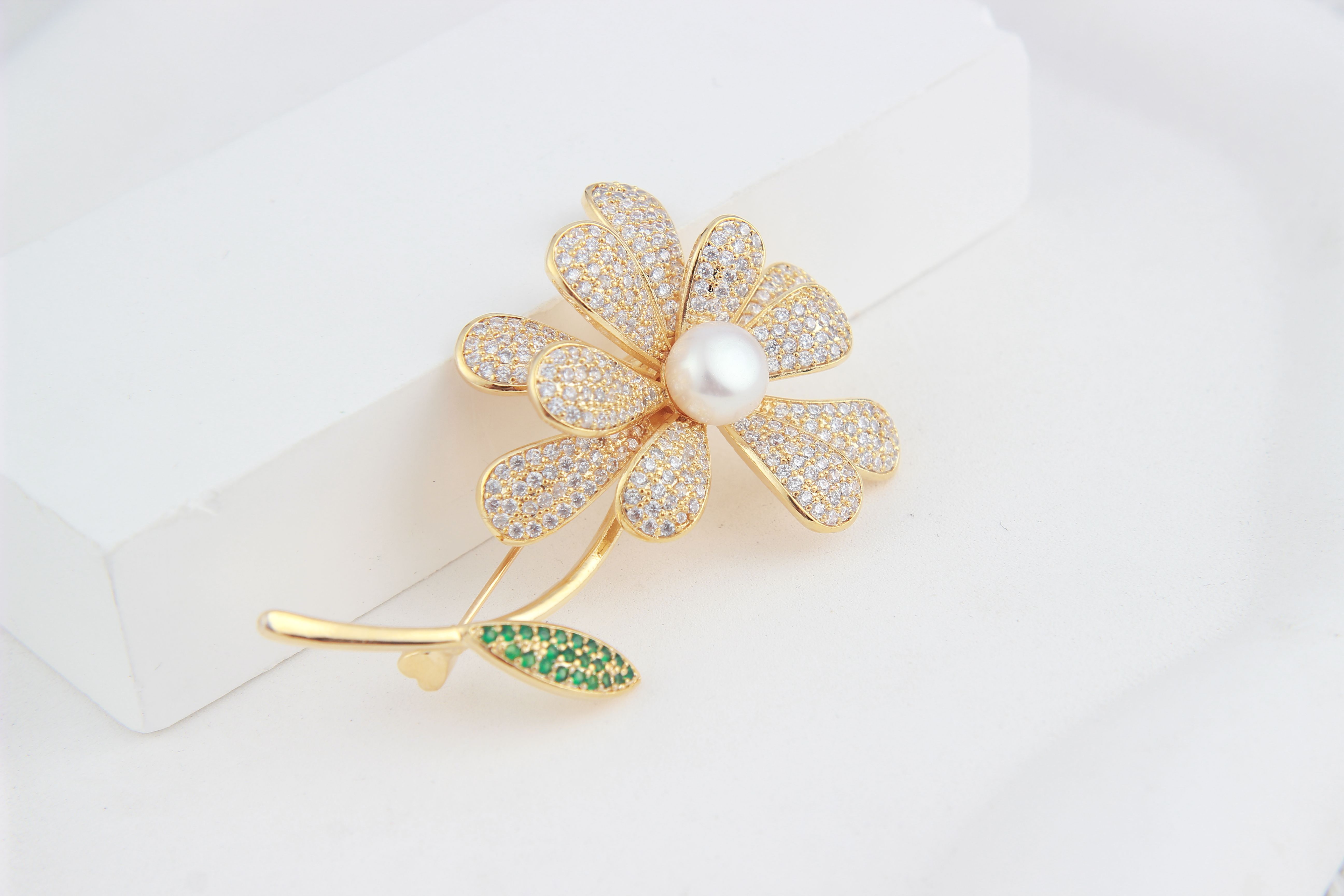 A close-up of a flower-shaped diamond and pearl brooch.