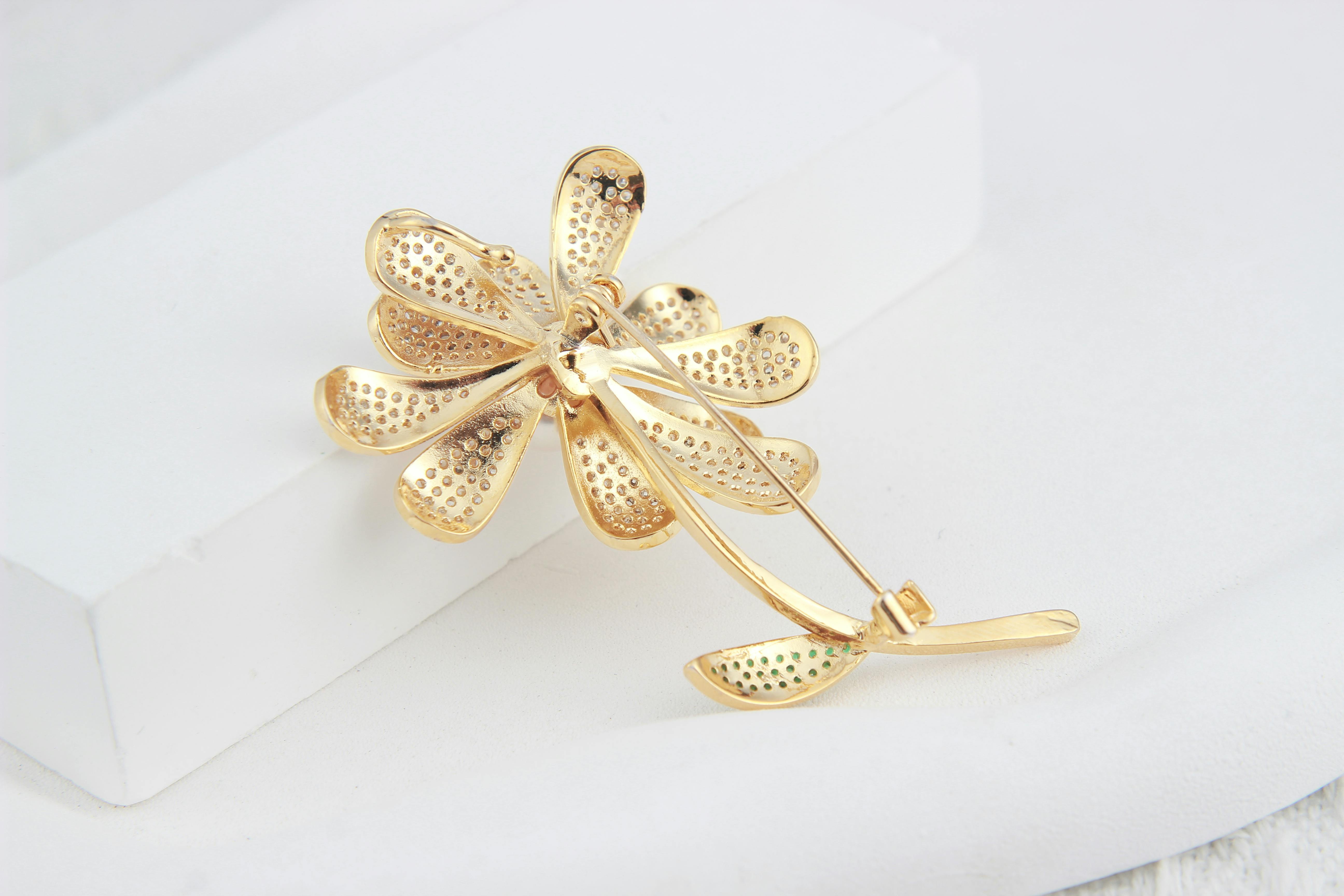 golden flower shaped brooch lying on a white background