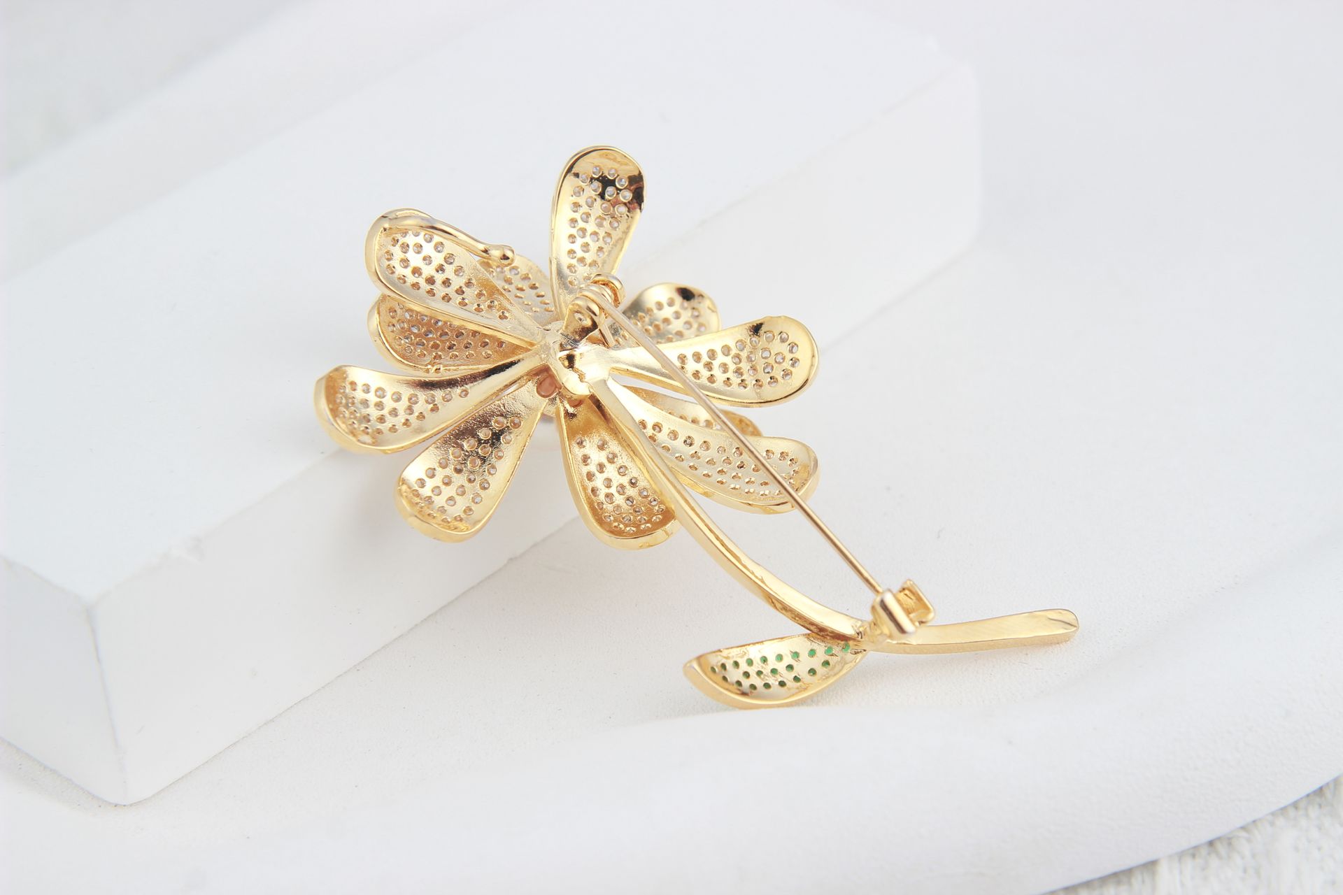 Luxury gold brooch with a flower design on white background, showcasing exquisite craftsmanship.