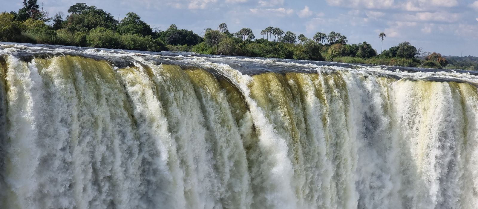 Stunning view of Victoria Falls cascading with vibrant energy, surrounded by lush greenery. — flights from Johannesburg to Victoria Falls