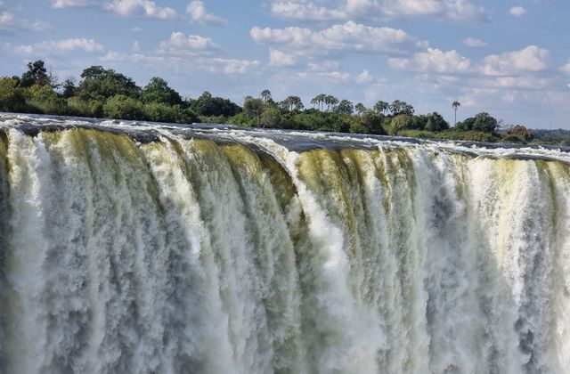 Stunning view of Victoria Falls cascading with vibrant energy, surrounded by lush greenery. — arriving in Victoria Falls