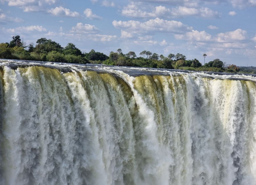Stunning view of Victoria Falls cascading with vibrant energy, surrounded by lush greenery.
