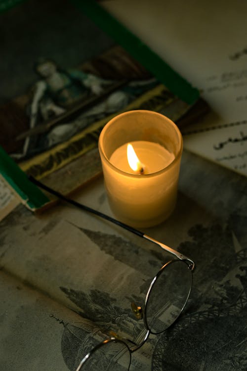 Eyeglasses near Burning Wax Candle