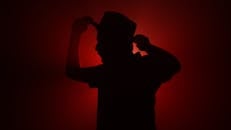 Silhouette of a Man Adjusting His Hat in Red Lighting