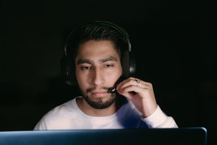 Brunette Man Sitting At A Computer And Wearing A Headset