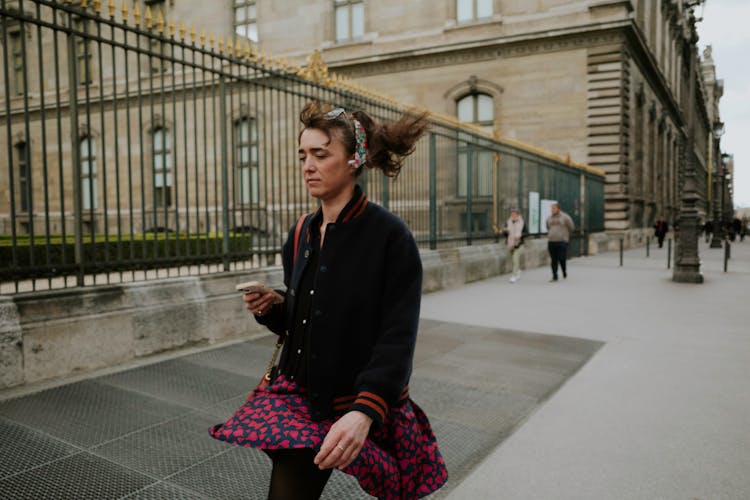 Young Woman Walking On The Street Listening To Music On Her Ear Bud Headphone