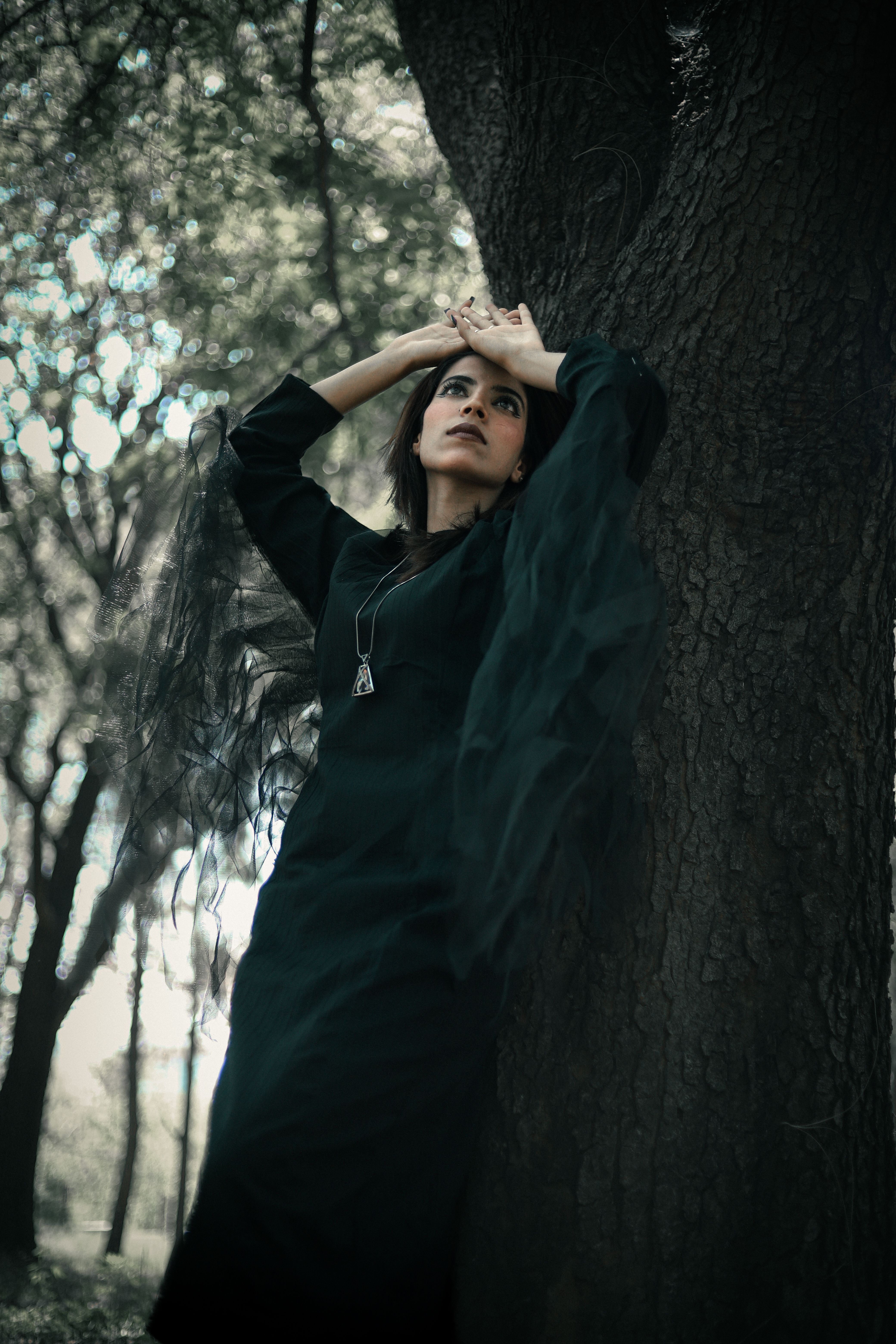 Model in a Black Dress Leaning Against a Tree · Free Stock Photo