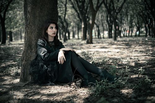 Free Young woman sitting by a tree in Islamabad park, dressed in black for a moment of relaxation. Stock Photo