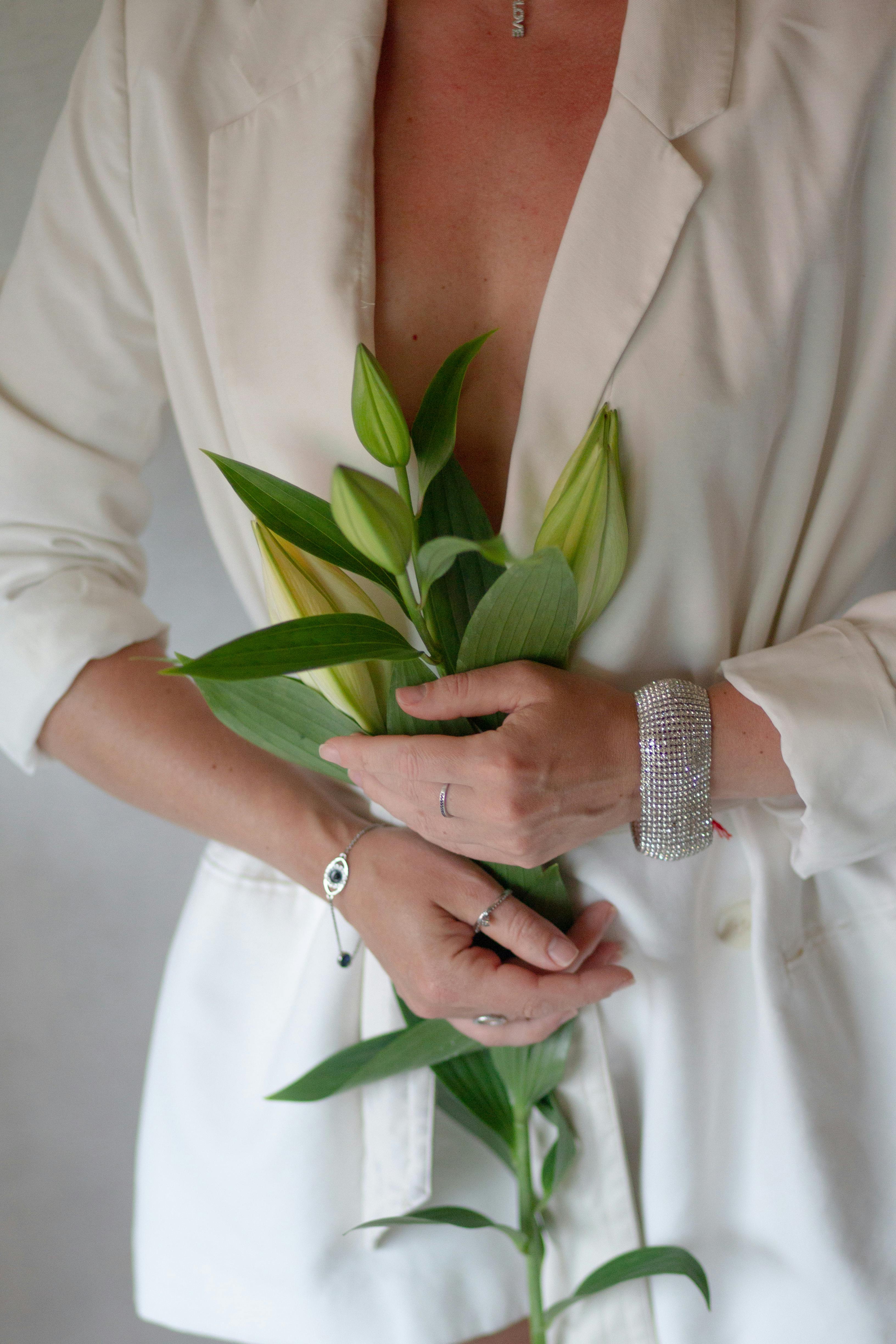 a woman in a white suit holding a bunch of flowers