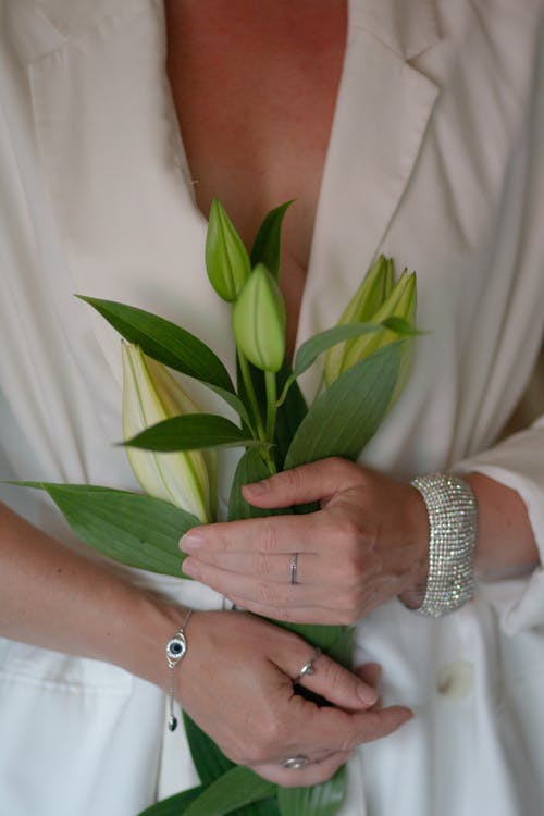 Woman Wearing Silver Jewelry Holding a Bunch of Lilies 