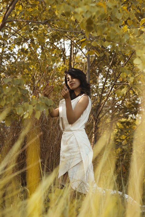 Free A woman in a stylish white dress enjoys nature among fall leaves in Islamabad, Pakistan. Stock Photo