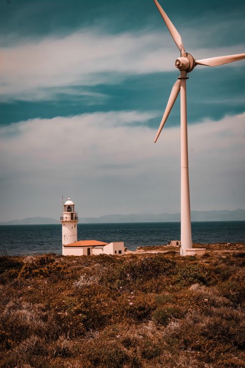 Free Scenic view of lighthouse and wind turbine on Bozcaada island, Türkiye, near the sea. Stock Photo