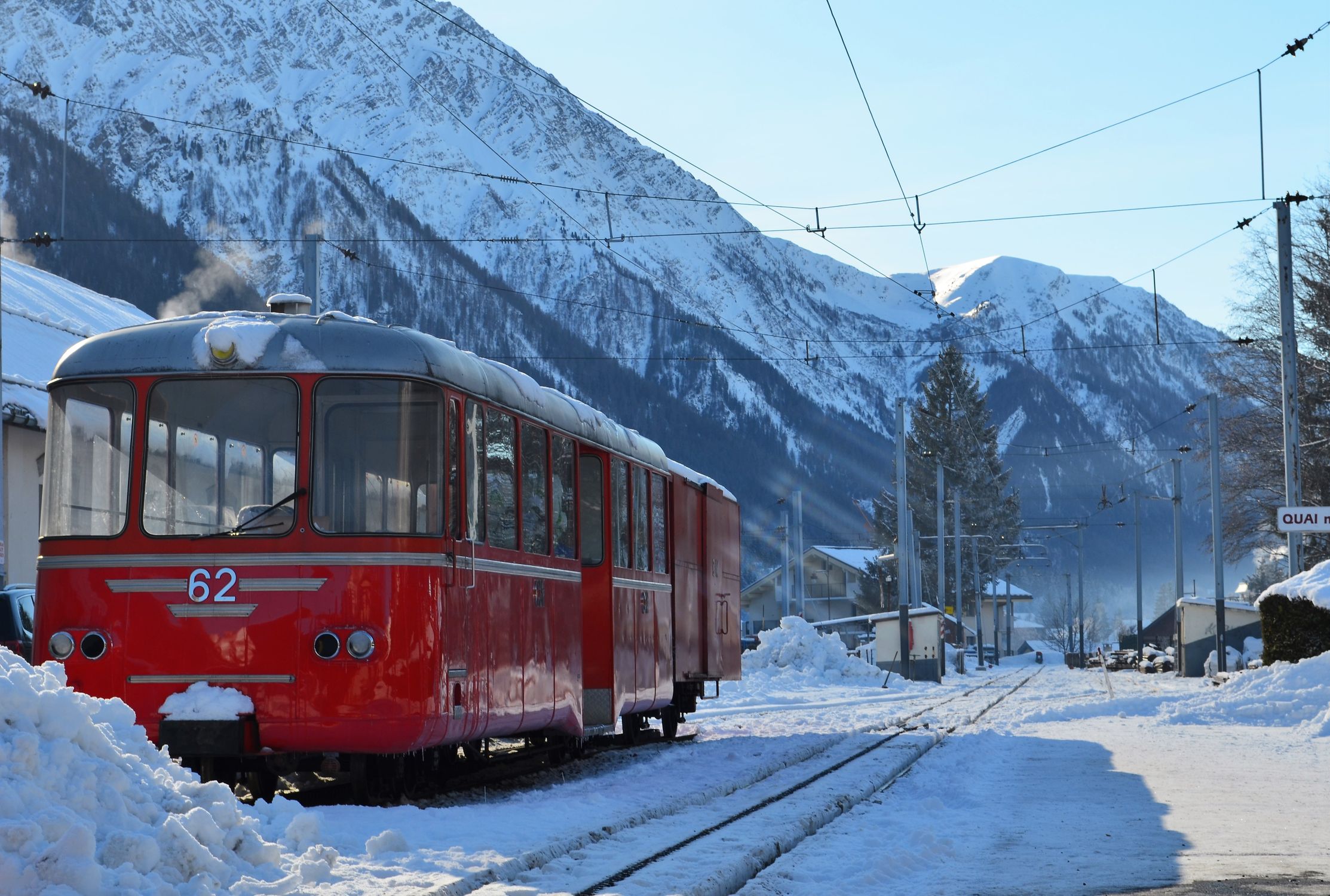 Red train in snowy Chamonix-Mont-Blanc, showcasing winter travel in the French Alps.
