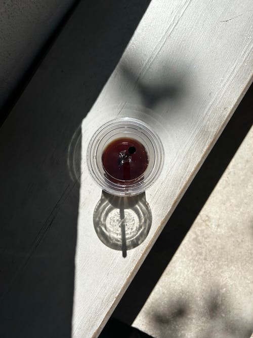 A Plastic Cup with Coffee Standing on a Wooden Surface