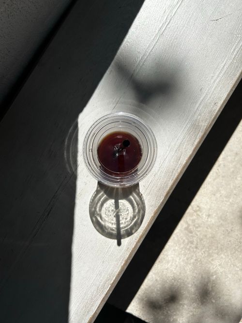 Free Top view of iced coffee in a plastic cup casting a shadow in bright sunlight. Stock Photo