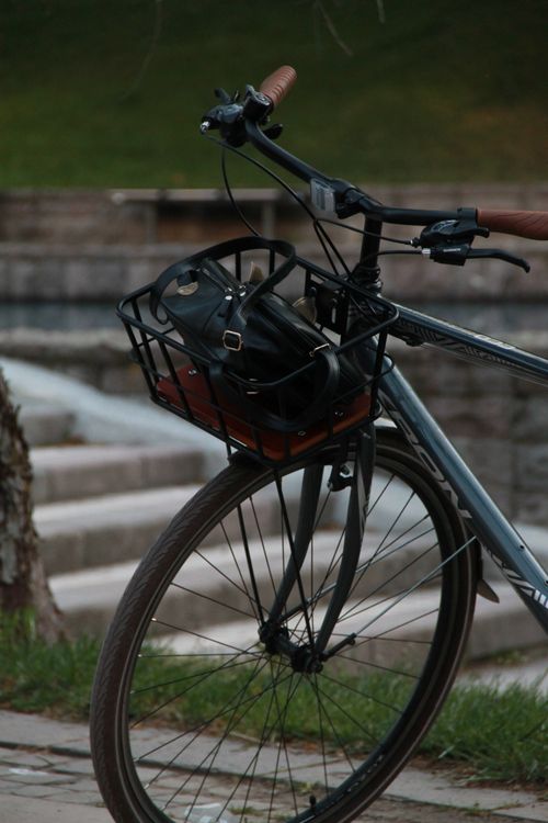 Free Close-up of parked urban bicycle with leather bag in basket near park steps. Stock Photo