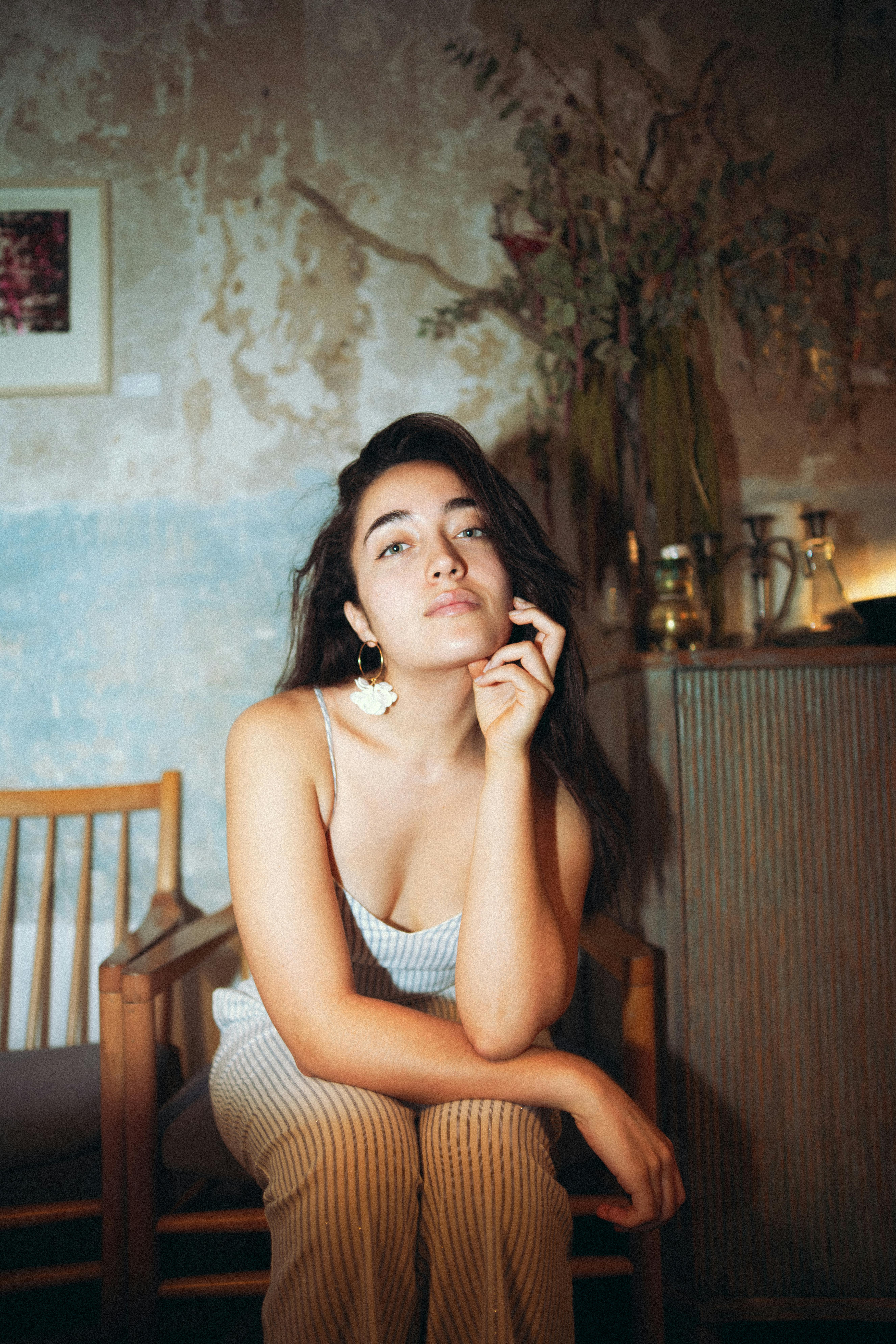 Portrait of a woman with long hair sitting confidently in a cozy indoor setting.