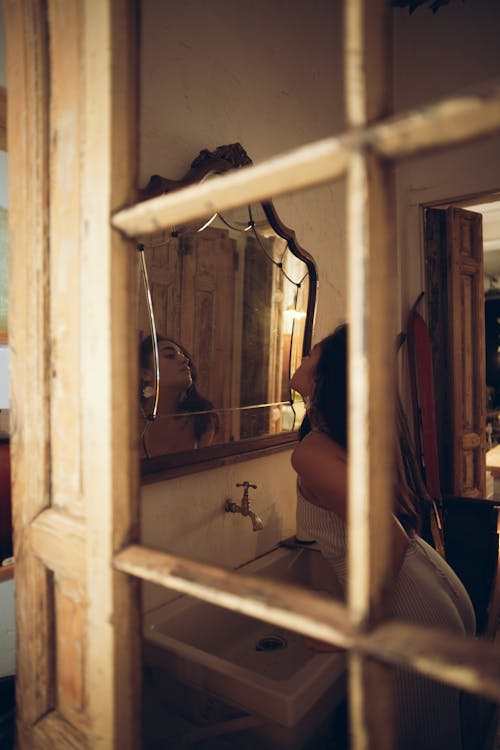 Young Woman Looking in the Mirror in a Vintage Bathroom 