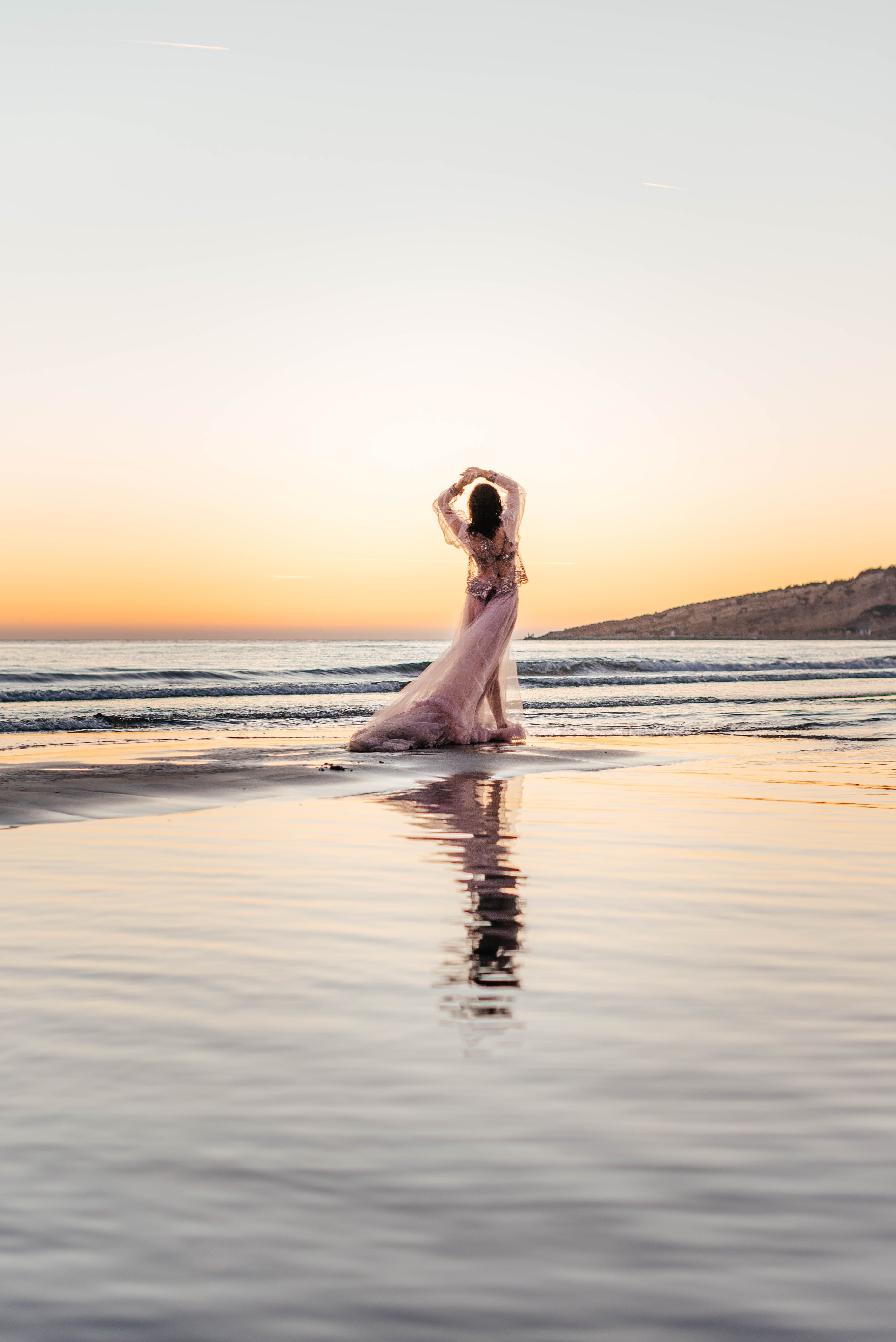 Woman in a Long Pink Dress Wading in the Sea on the Beach at Sunset ...