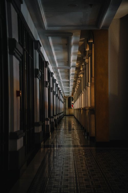 Free Dramatic low-light shot of a long hallway with classical columns and polished floor. Stock Photo