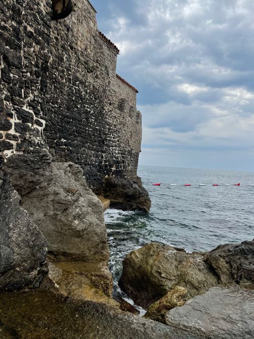 Free A rugged stone fortress stands above crashing waves, with dramatic cloudy skies overhead. Stock Photo