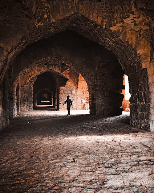 Free stock photo of cave, light rays, man walking