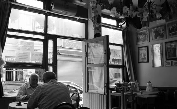 A serene black and white image of elderly men dining in a cozy café.