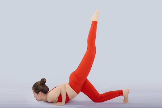 Woman in red sportswear practicing yoga pose indoors, showcasing flexibility and balance.