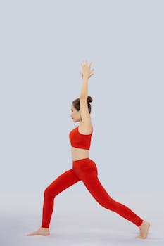 Side view of a woman performing yoga pose in red sportswear against a plain background.
