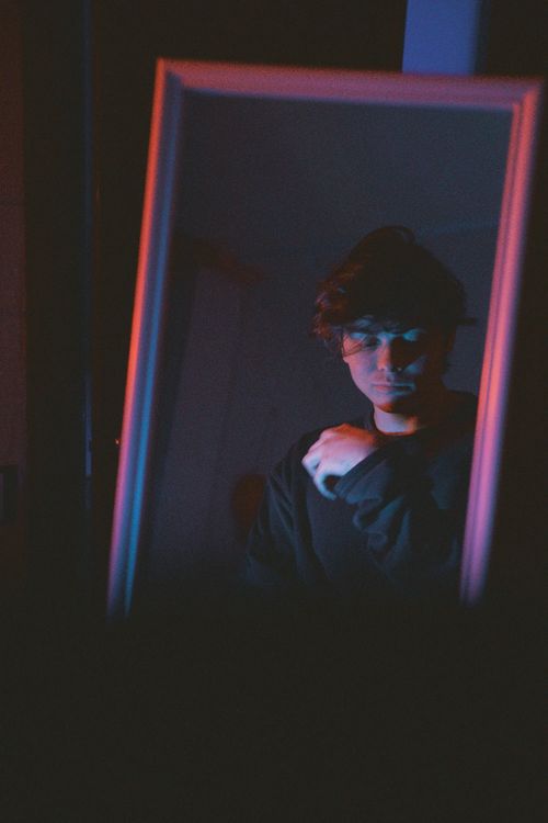 Free A contemplative man gazing into a mirror with dramatic lighting in Moscow. Stock Photo