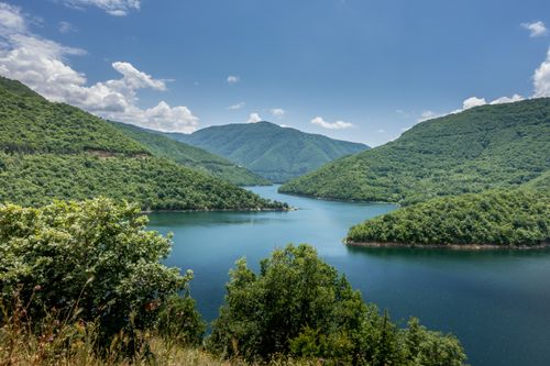 Free Beautiful view of the lush Rhodope Mountains and a clear water reservoir under a blue sky. Stock Photo