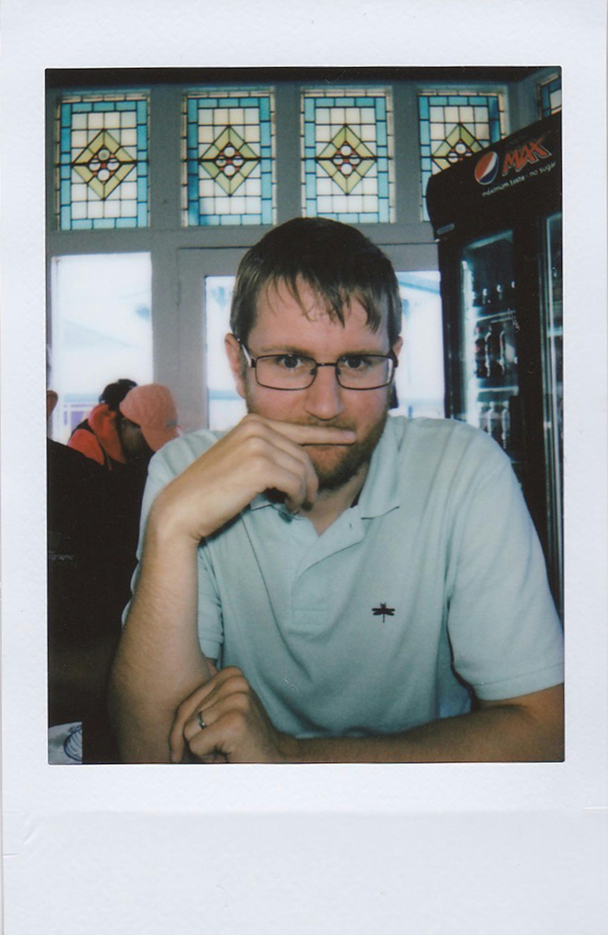 Casual portrait of a young man with glasses at a restaurant table.