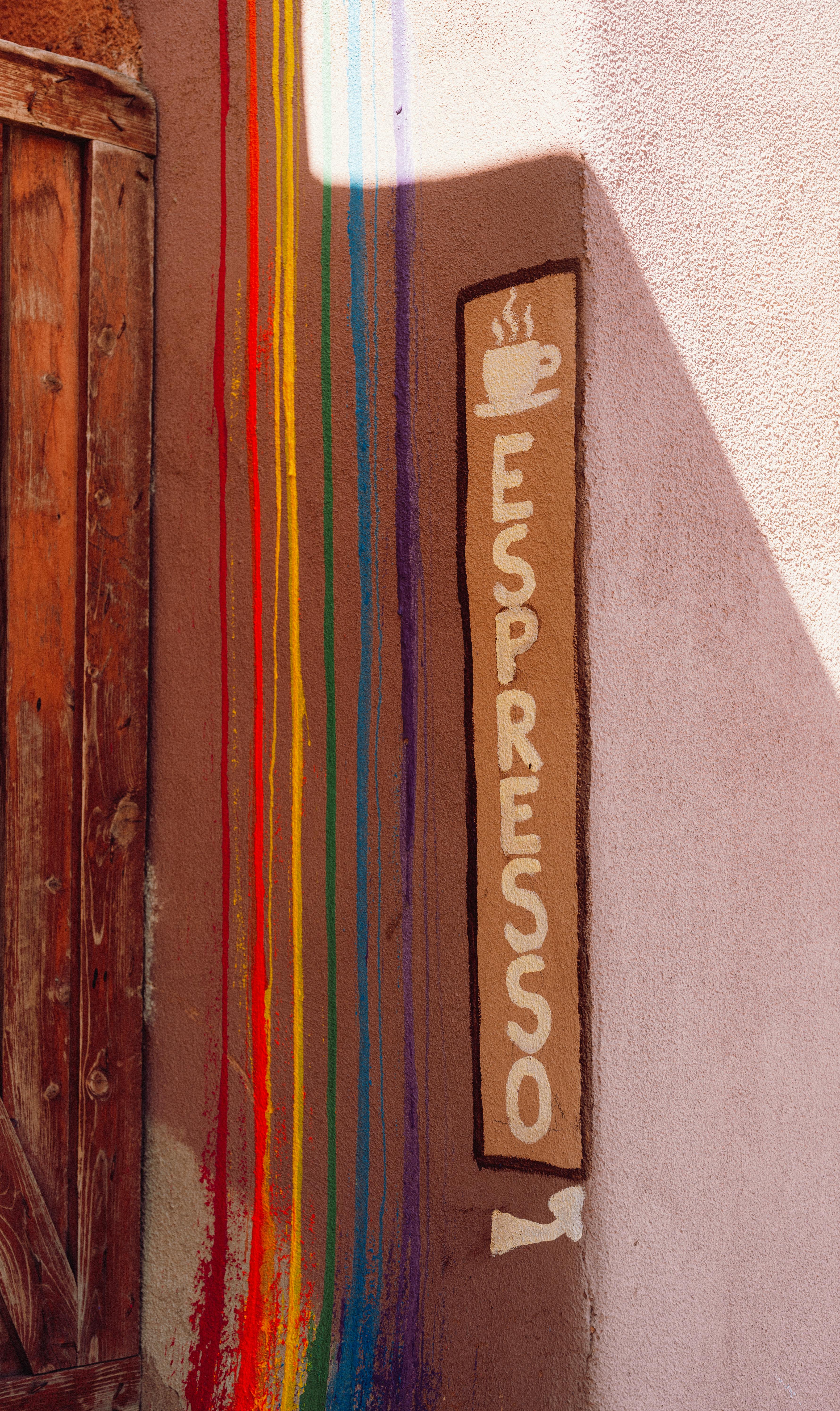 Vertical shot of a colorful espresso sign painted on a café wall with rainbow stripes.