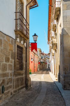 Explore the historic charm of a cobblestone street in Guimarães, Portugal, bathed in sunlight.