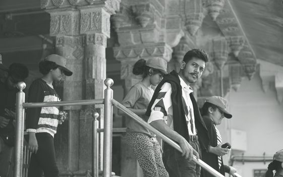 Black and white photo of tourists in a historic Indian palace with intricate stone pillars.