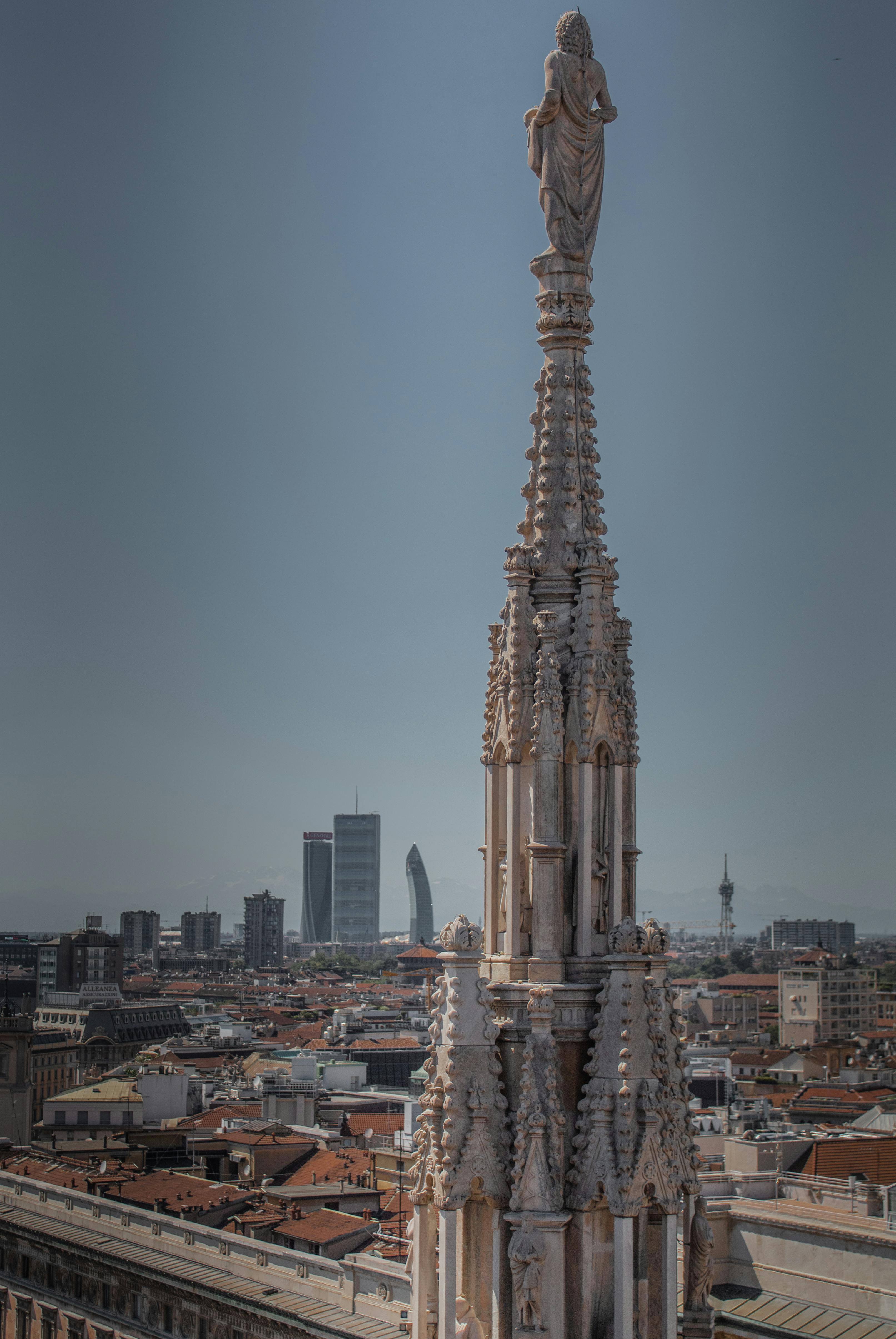 A breathtaking shot of Milan Cathedral's spire with city skyline backdrop, showcasing Gothic architecture.