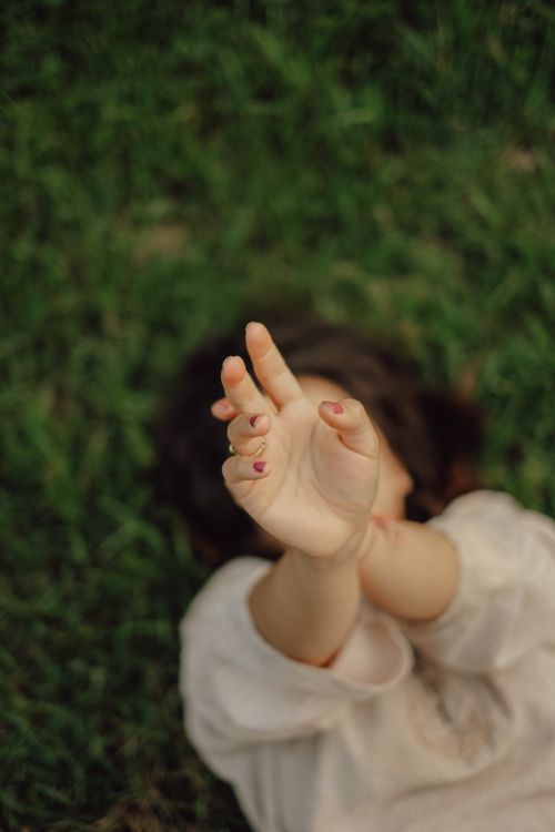 Free A woman lying on grass, arms outstretched, enjoying a summer day outdoors. Stock Photo